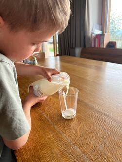 Kind, das sich Milch einschenkt