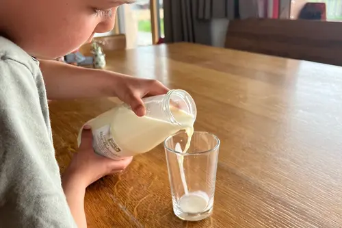 Kind, das sich Milch einschenkt